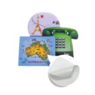 A collection of three mouse pads, one shaped like a green vintage phone, a round one with Paris and the Eiffel Tower design, and a rectangular one featuring a map of Australia. A close-up insert shows the textured back of a pad.