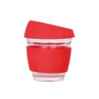 A transparent, reusable cup with a red silicone band and lid. The cup has a modern, compact design, suitable for hot beverages.