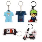 Five keychains are displayed: a light blue shirt, a dark blue shirt with Queensland Ambulance Service, a cartoon figure in green with a red bag, a gaming controller with FGTEEV, and a white rescue motorcycle with Bambulance.