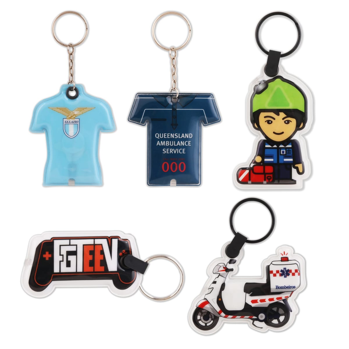 Five keychains are displayed: a light blue shirt, a dark blue shirt with Queensland Ambulance Service, a cartoon figure in green with a red bag, a gaming controller with FGTEEV, and a white rescue motorcycle with Bambulance.