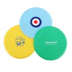 Three colorful frisbees overlap on a white background: a yellow one with a cartoon bear, a blue one with a circular target pattern, and a green one with Simparica works fast and lasts text.