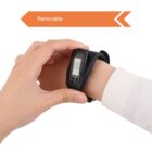 A person’s hand adjusting a black digital pedometer on their wrist. The device has a small display, and an orange banner above reads Removable with an arrow pointing right. The person is wearing a white sleeve.