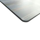 Close-up of the corner of a rectangular object, possibly a card or photograph, with an image of a landscape slightly visible. The surface appears glossy, and the edge is rounded. The background is white.