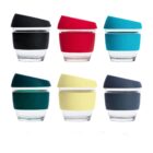 Six glass cups with lids and silicone bands in various colors: top row in black, red, and turquoise; bottom row in teal, cream, and navy. Each lid is tilted slightly to one side.