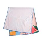 A white towel with blue edges, partially folded to reveal a colorful, cartoon-like design underneath, featuring bright shapes and a hint of a red crab.