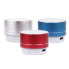Three portable Bluetooth speakers in silver, red, and blue. Each speaker has a cylindrical shape with control buttons and a USB port on the front side. White bases support the colorful tops.