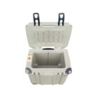 Open gray cooler with black handles, shown from above. The interior is empty, and two dark latches are visible on the lid. The exterior has a rugged, boxy design. A warning label is attached to the inside of the lid.