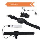 A black smartwatch with an orange charging port arrow above. Below are a detachable charging cable and a portable power bank. The components are arranged on a white background.
