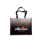 A black tote bag featuring the ellesse logo in white with an orange and red semi-circle design above. The word ITALIA is printed below in white. The bag has two black handles and a gradient background.