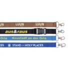 Four lanyards are displayed horizontally. From top to bottom: brown with LUUN SUBLIVIST, black with aus&raus, light blue with Neustadt an der Orla, and dark blue with STAND YE IN HOLY PLACES. Each has a metal clip.