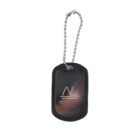 A black dog tag with a silver logo featuring the letters NL and two horizontal lines beneath. It is attached to a metal ball chain. The tag has a glossy finish.