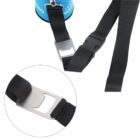 Close-up of a black nylon strap with a metal bottle opener attached. The strap has a plastic buckle near the metal opener. A blue item is partially visible in the background, connected to the strap by a keyring.