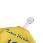 Close-up of a yellow item with blue Cyrillic text that reads Слава Україні! (Glory to Ukraine!). A transparent suction cup is attached to it.