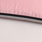Close-up of a pink fabric with a silver zipper partially unzipped, on a white surface.