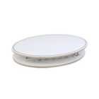 A white, oval-shaped tabletop with a slightly raised rim sits on a similar oval base. The tables design appears modern and minimalist, with a hollow space visible between the top and the base.