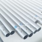 Close-up of several silver metal pipes arranged parallel to each other. Each pipe has a small blue number printed near the end. Tiny screws are visible on the surface of the pipes, which are laid on a light surface.