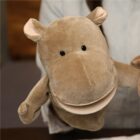 A person holding a brown hippopotamus hand puppet. The puppet has a wide open mouth, two small black eyes, and rounded ears. The background is blurred, focusing on the puppet.