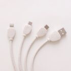 A white multi-connector cable with four different connectors: Lightning, micro USB, USB-C, and standard USB. The cables are placed on a plain white background.