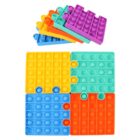 Colorful pop-it fidget toys in interlocking puzzle pieces. Each piece is a different color: purple, orange, green, and blue. They are arranged in a square with some pieces slightly overlapping.