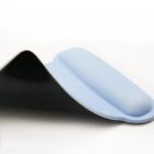 Close-up of a white silicone gel object with a smooth, curved surface on a black, glossy background. The object appears to have a slight fold or bend, revealing its thickness and flexibility.