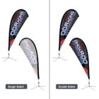 A comparison of single-sided and double-sided teardrop banners for OD Racing. The single-sided banner shows text on one side, while the double-sided banner displays text on both sides. Both banners are black with red, blue, and white accents.