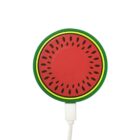 A round phone charger designed to look like a watermelon slice. It has a red center with black seed-like spots, surrounded by a green and yellow rind. A white charging cable is attached at the bottom.