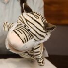 A person holds a zebra-striped plush hand puppet. The puppet has a wide, light pink snout and small, black eyes. The person’s hand is inside the puppet, making it appear animated on a blurred background.