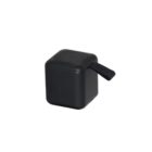 A small, black, cube-shaped portable speaker with a perforated top for sound output and a small handle or loop on the side.