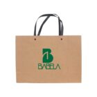 A brown paper shopping bag with black handles. The bag has a green logo featuring the letter B and the word BABELA printed below it.