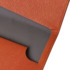Close-up of a textured orange book cover with a cutout detail, revealing a smooth gray layer beneath. The design features a straight edge with a curved notch in the corner of the cover.
