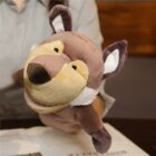 A person holding a brown and beige wolf puppet with large ears and a smiling face. The puppet appears to be made of soft fabric. The person is partially visible and is holding the puppet above a table or surface with papers.