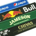 Rubber bar mats with logos for Pepsi, Red Bull, Jameson Irish Whiskey, and Chivas Regal. Each mat has distinctive colors and designs, with prominent branding.