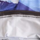A close-up of a fabric with a mountain print at the top and a plain white bottom section. The fabrics are stitched together with a zigzag seam, showing contrasting textures and colors.