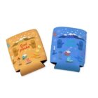 Two colorful drink koozies with winter-themed illustrations. The orange koozie features brown baskets, skis, a candle, and snowflakes. The blue koozie has similar elements with a mountain, cabin, and shoes. Both say God påske.