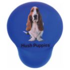 A blue object with a Basset Hound image on it. The text Hush Puppies is printed below the dog. The object is shaped like a guitar pick.