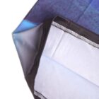 Close-up of a folded blue and black fabric, showing a corner with visible white stitching along the edge. The fabric has a gradient from dark to light blue, with a smooth texture.