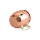A shiny copper mug with a golden handle rests on its side. The reflective surface shows a soft reflection of a light source from above.