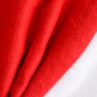 Close-up of a soft, red and white fabric, likely a Santa hat, showing the vibrant red cloth against the fluffy white trim. The texture appears soft and plush, suggesting a cozy material.
