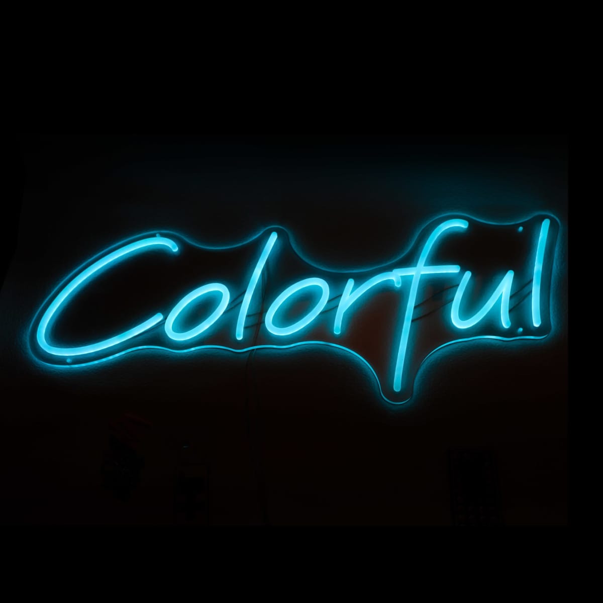 Neon sign with the word Colorful in bright blue on a dark background.