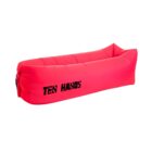 Red inflatable lounger with Ten Hands written on the side in black text. The lounger is fully inflated and features a simple, elongated design with seams and a slightly elevated headrest.