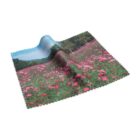 A printed fabric cloth featuring a vibrant field of pink flowers with green grass. The cloth is slightly folded, showing a landscape image with trees and a blue sky in the background.