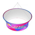 A circular, hanging banner with a gradient of pink, purple, and blue. It features text that reads Hot Sale! NEW Arrival in bold letters. The banner is suspended by cables from the top.