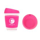 A pink reusable cup with a lid is shown. The cup has a transparent base and a pink silicone sleeve with a logo that reads LIONICA STUDIOS and features a stylized lions head. The lid is placed next to the cup.
