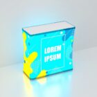 A brightly lit, cube-shaped display with abstract blue and yellow patterns and the text Lorem Ipsum in the center. The background is a plain, light gray surface.