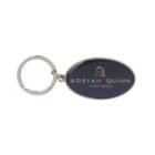 Oval-shaped keychain with a silver ring, featuring a dark background. The text reads Adrian Quinn Car Sales in white, with a stylized letter Q in gold above the text.