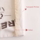 Close-up of a white fabric bag with a beige seam, labeled Food grade TPU liner and Cotton. The words are printed on the bag in a dark color, partially visible.
