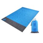 A large blue picnic mat with a dark gray border is laid out flat. A small pouch in the same colors is placed on the mat. Next to the mat is a blue carry bag with a gray drawstring.