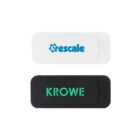 Two webcam covers are shown. The top one is white with the text escale in blue. The bottom one is black with the text KROWE in green. Both have a rectangular shape with rounded edges.
