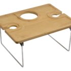 A wooden portable picnic table with collapsible metal legs. It has two cup holders, one bottle holder, and a flat surface for serving food or placing items.