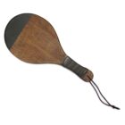 A wooden paddle with a smooth, circular head and a dark, textured handle, featuring a looped cord at the end for hanging. The paddle has a two-tone design with a lighter wood body and dark head.